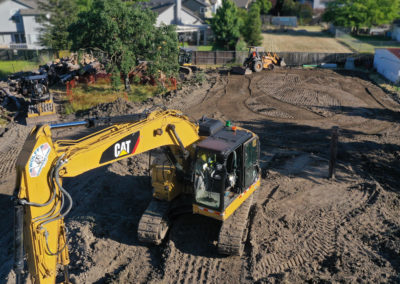 excavator parked on dirt pile with bucket loader and grading attachment in background on site preparation